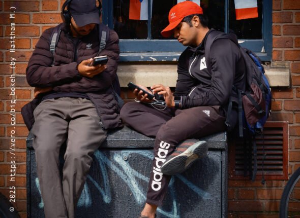 Delivery Drivers sitting on telephone box checking out phones