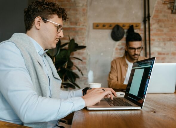 Two professionals working on laptops in a modern workspace