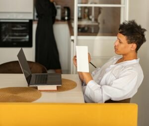 Business professional in casual attire taking notes during an online meeting at home