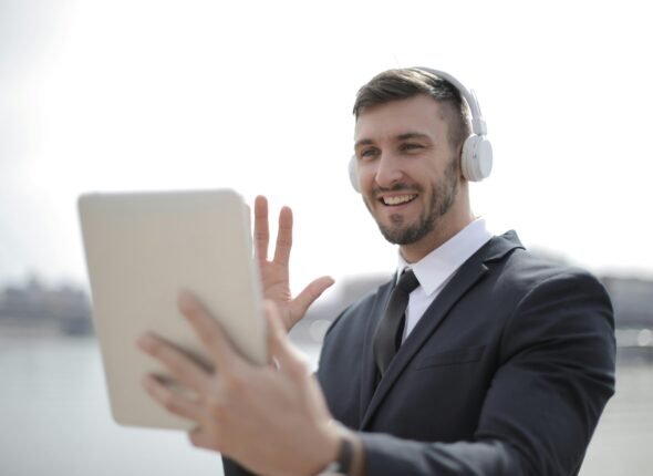 Confident businessman in a suit attending an online meeting with headphones and tablet