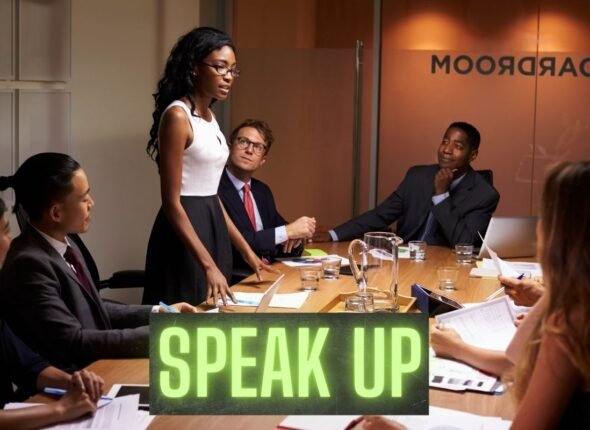 Confident businesswoman standing and speaking during a boardroom meeting, showcasing assertive professional communication.